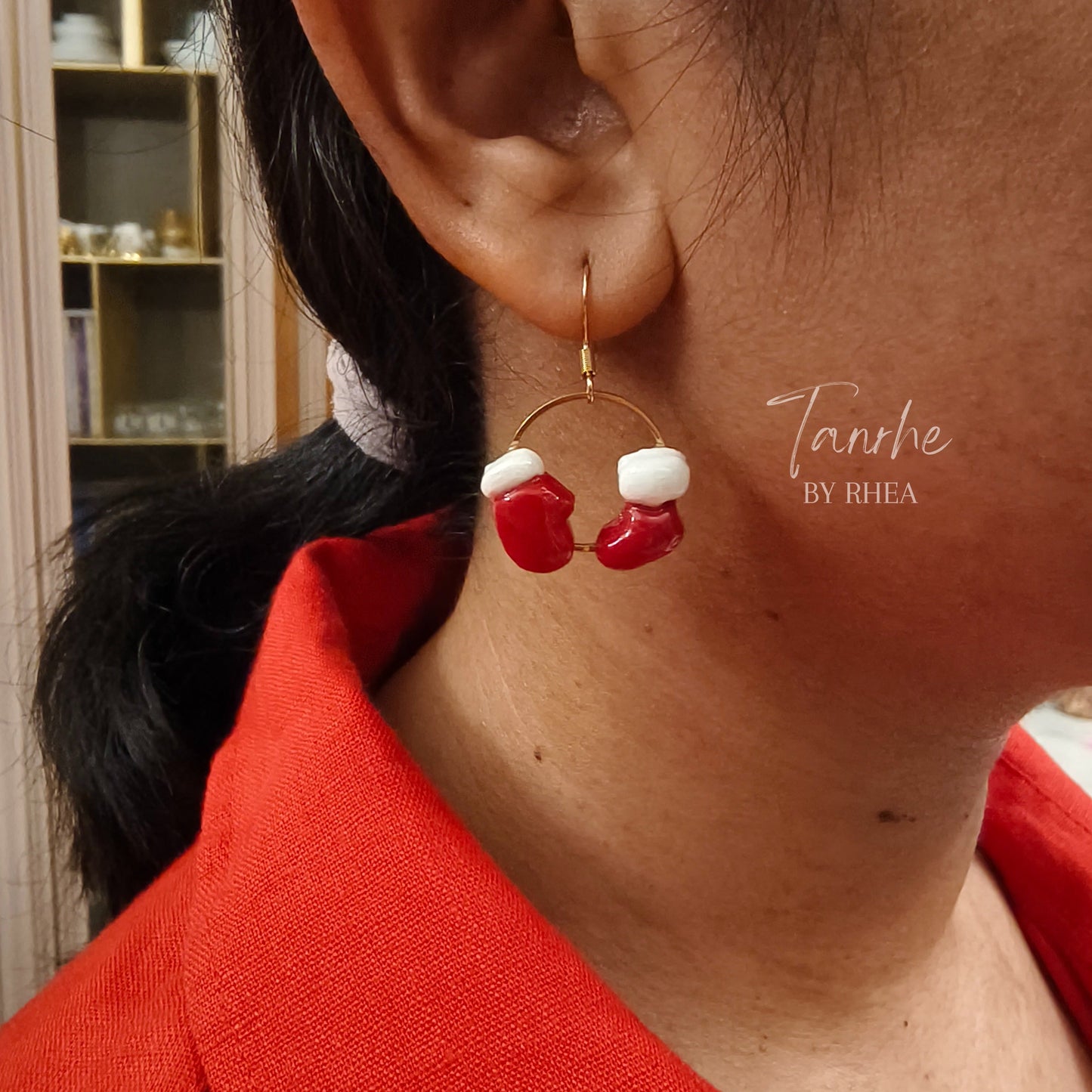 Close-up of an ear wearing a red and white christmas sock and glove earring 